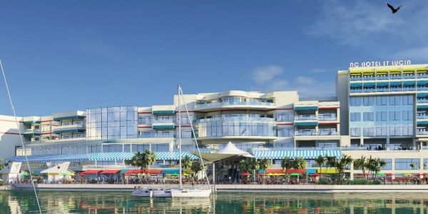 Modern waterfront hotel with balconies and sailboats on a sunny day.