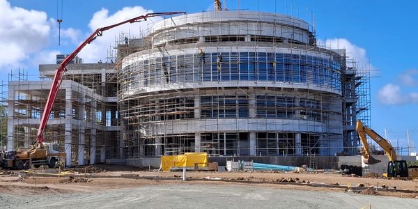 Large round building under construction with scaffolding and machinery.