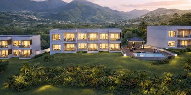 Modern residential buildings with illuminated windows in a mountainous landscape at dusk.