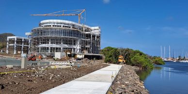 Construction site of a modern building near a waterfront with boats.