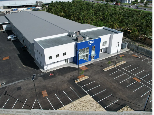 A modern TPM building with an empty parking lot and surrounding palm trees.