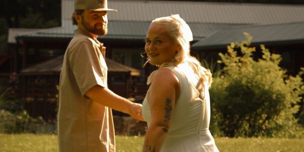 Couple holding hands outdoors, smiling and enjoying a sunny day.