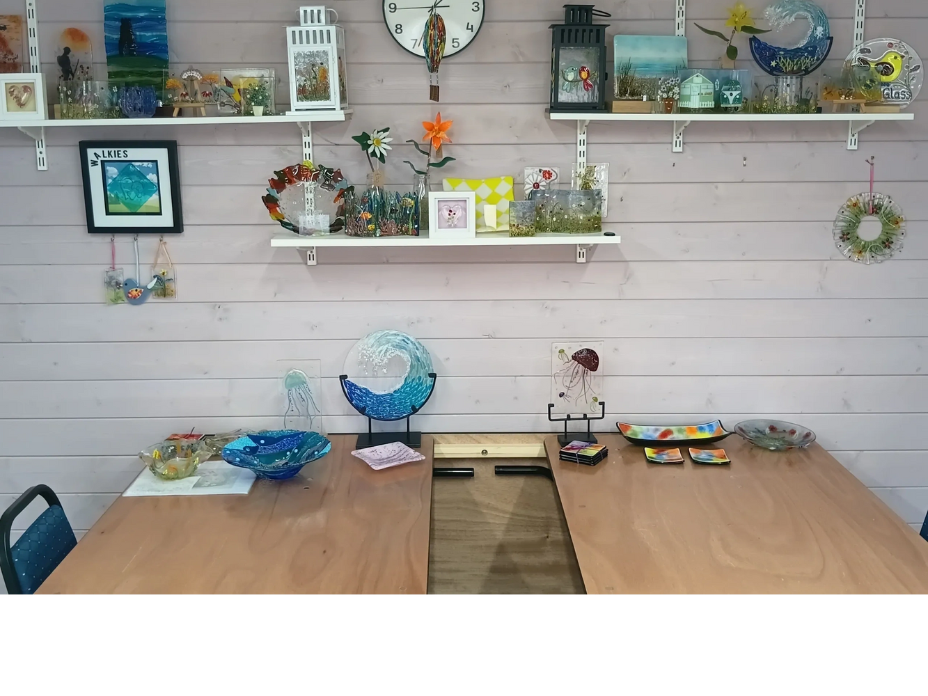 Colorful glass art pieces displayed on shelves and tables in a cozy room.
