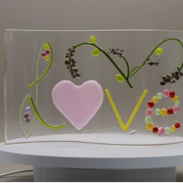 Decorative glass panel spelling LOVE with floral and heart designs.