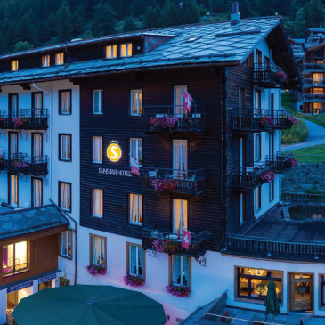 Charming Swiss hotel with flower-filled balconies at dusk.