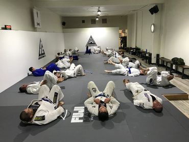 A group of jiu jitsu students laying on the floor