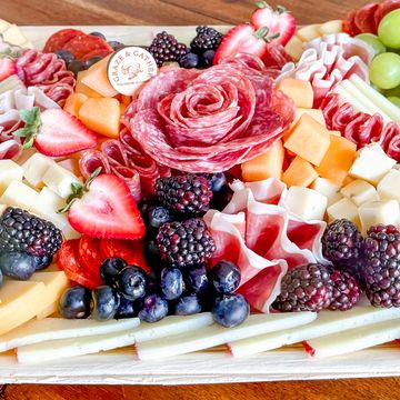 Colorful charcuterie board with fruits, cheeses, and meats artfully arranged.