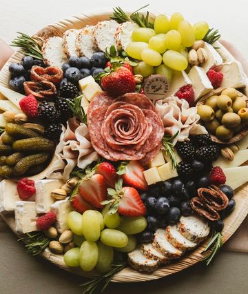A beautifully arranged charcuterie board with fruits, cheeses, and meats.