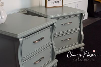 Close-up of vintage gray bedside tables with silver handles.