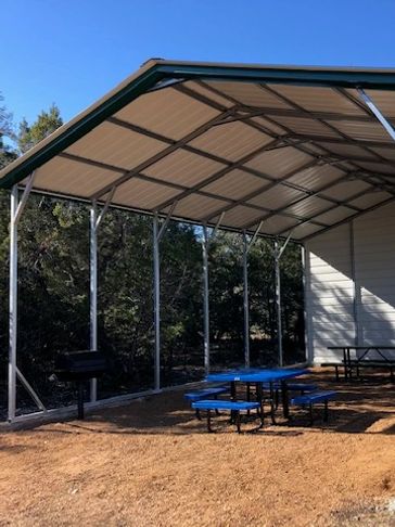 A shaded picnic pavilion with picnic tables and grills.
