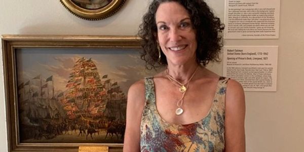 Woman smiling in front of a framed historical painting in a museum.