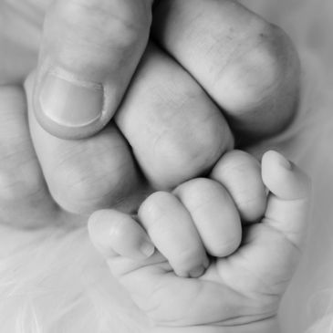 A close-up of two fists bumping together with a furry white background, a father and his baby.