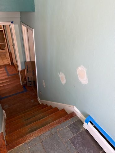 Staircase with light blue walls and patches being repaired.