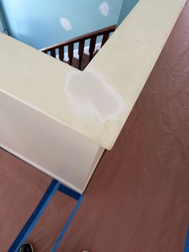 Close-up of a patched corner on a beige railing above a staircase.