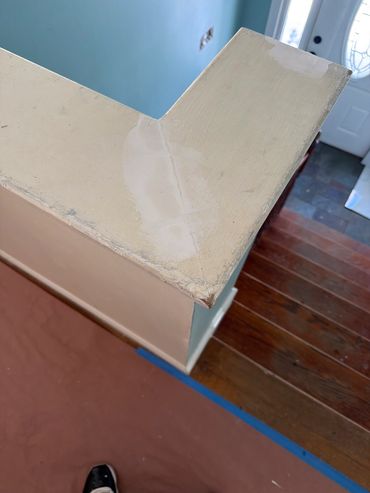 Corner of a painted wooden railing with patch repairs.