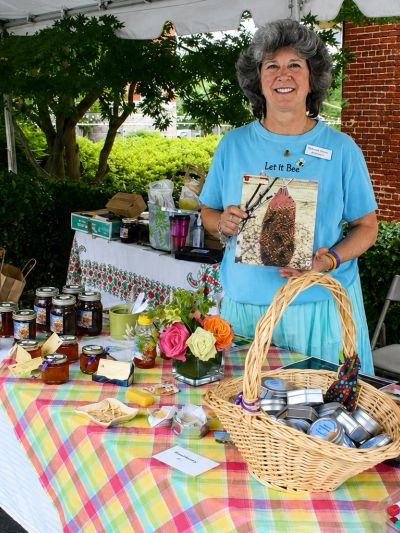 Woman at outdoor market stall selling honey products.