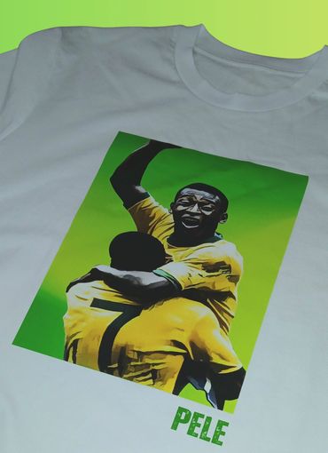 White t-shirt featuring a colorful graphic of Pele celebrating a soccer moment.
