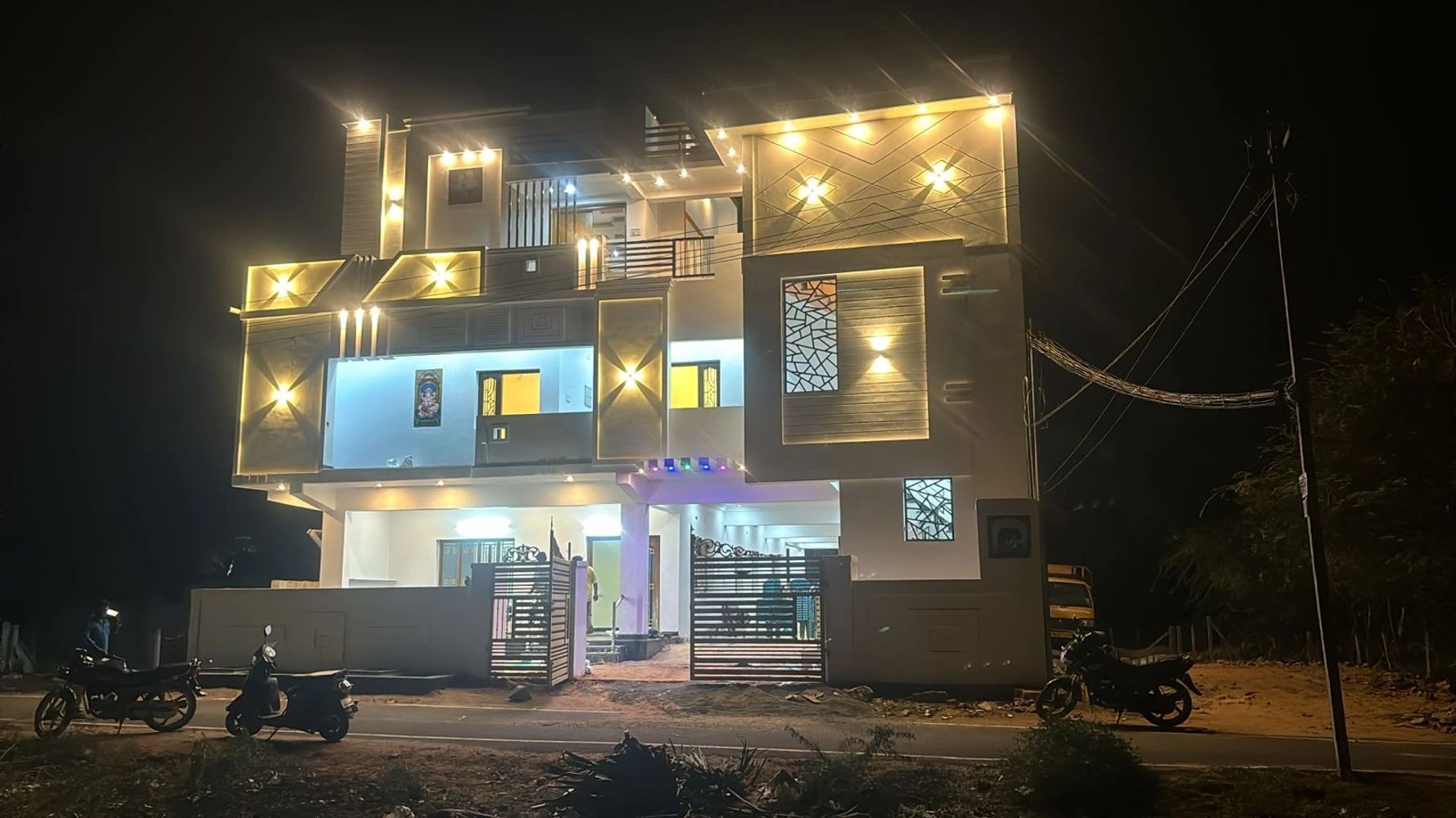 Modern two-story house illuminated with decorative lights at night.