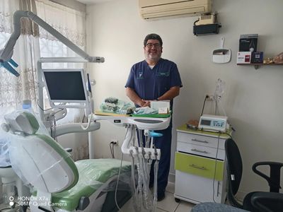 A smiling dentist in a dental clinic with equipment and chair.