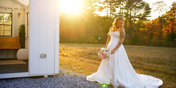 A bride poses in front of a golden sunset on her wedding day.