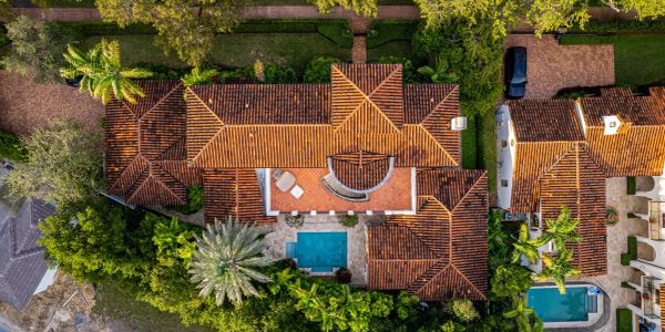 Aerial view of a luxurious house with a pool and tiled roof.