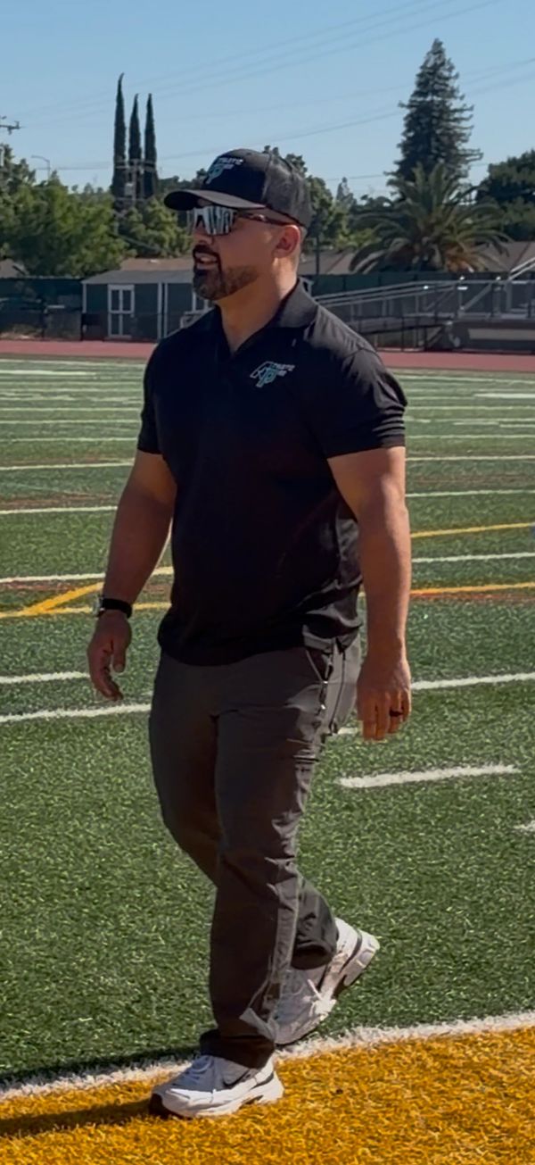 Man walking on a football field in athletic attire.