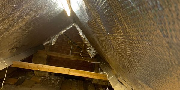 Insulated attic space with exposed beams and brick wall.