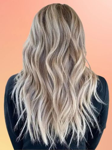 Long wavy ash blonde hair with subtle highlights on a black top.