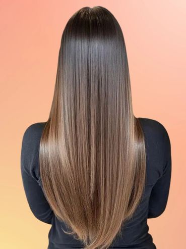 Woman with long, straight, shiny ombre hair against a peach background.