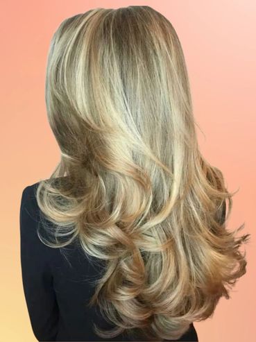 Long, voluminous blonde hair with soft curls against a peach gradient background.