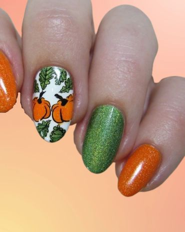 Festive nails with orange, green glitter, and pumpkin leaf designs in nail salon