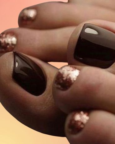 Close-up of toes with glossy black and glittery copper nail polish.