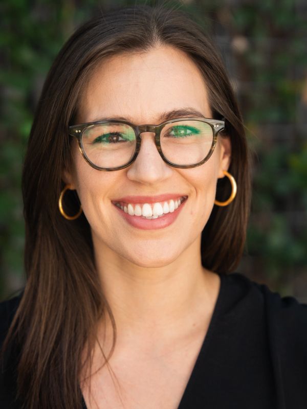 Smiling woman wearing glasses and hoop earrings.