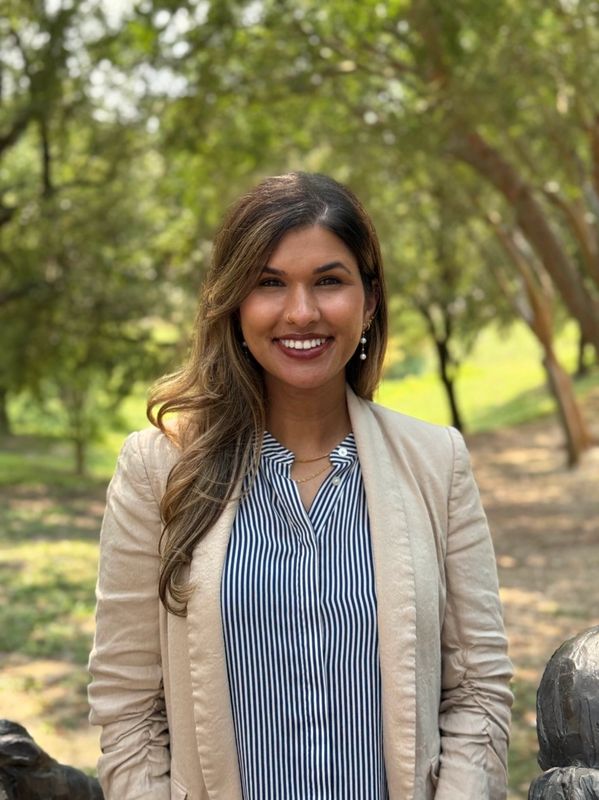 Smiling woman in beige blazer outdoors.