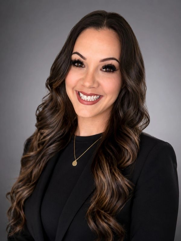 Professional woman with long wavy hair in black attire smiling.