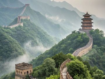 The Great Wall of China winding through lush green mountains under misty skies.