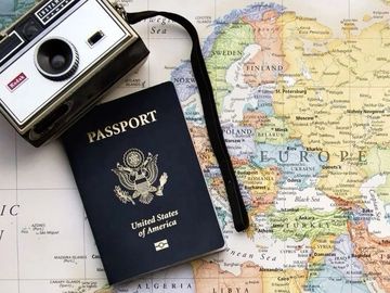 Travel essentials: a vintage camera and a US passport on a world map.