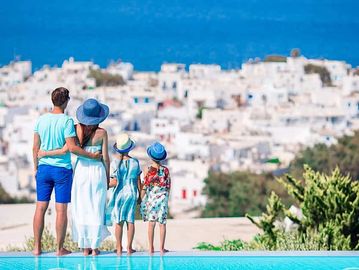 Family of four overlooking a picturesque white village on a sunny day.