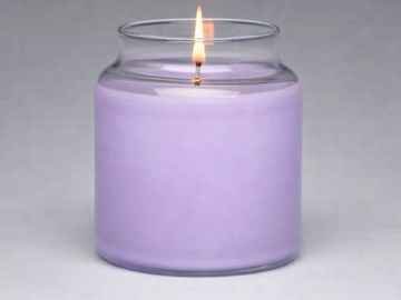 Lit purple candle in a clear glass jar.