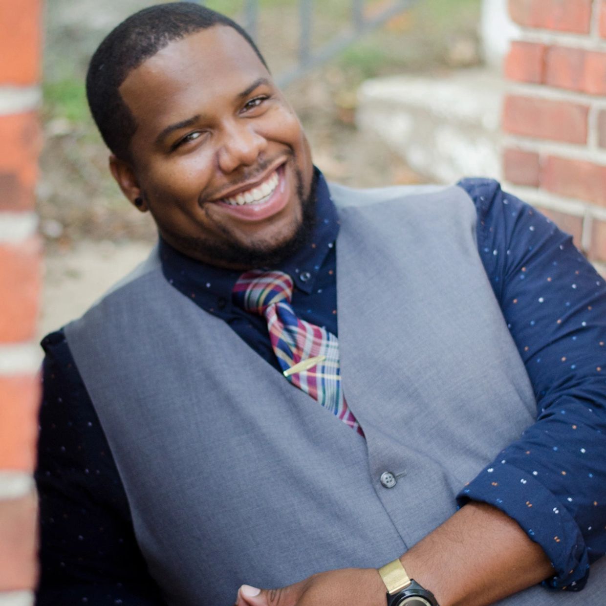 Smiling man wearing a grey vest and colorful tie.