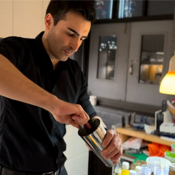 Man preparing a drink with a cocktail shaker in a modern kitchen.
