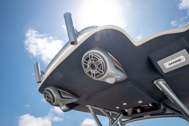Boat tower with mounted speakers and rod holders under a sunny sky.