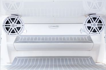 White marine speakers mounted on a boat deck with striped flooring.