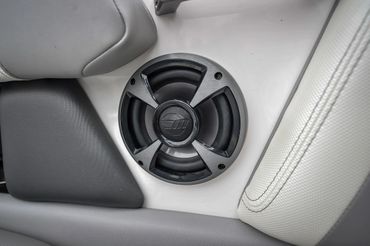 Close-up of a JBL speaker installed between gray and white seats.