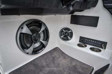 Close-up of speakers and control panel in a white interior with carpet.