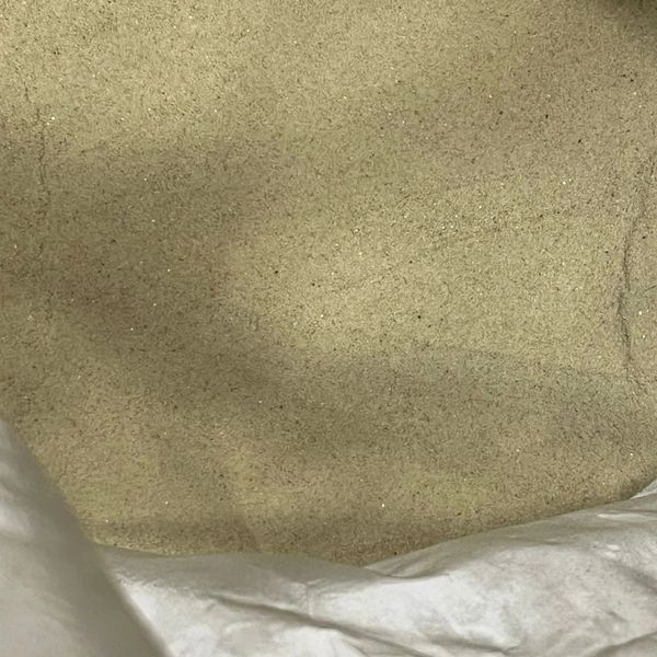 Close-up of a beige granular powder inside a white sack.