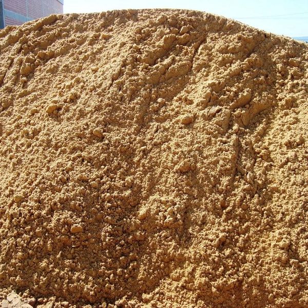 A large pile of loose, brown soil or sand outdoors.