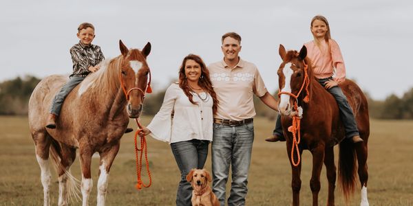 Family with two kids, two horses, and a dog outdoors.
