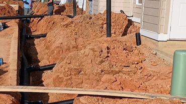 Construction site with trench and piping near residential buildings.