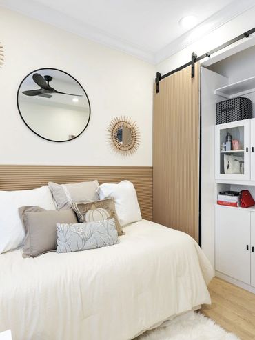 Cozy bedroom with neutral tones, decorative mirrors, and organized storage cabinets.